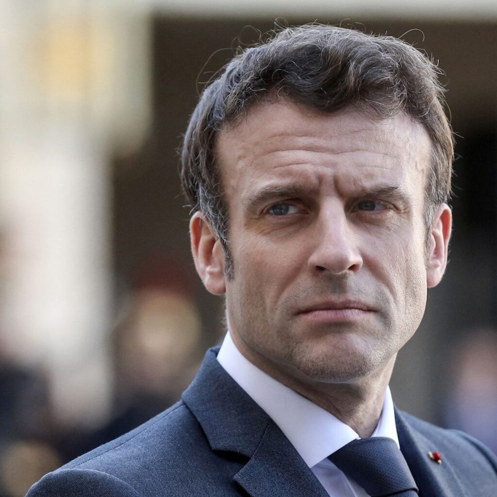 Emmanuel Macron souriant lors d'une apparition publique, au cœur des rumeurs sur sa chevelure